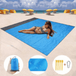 a woman lying on a blue blanket on a beach